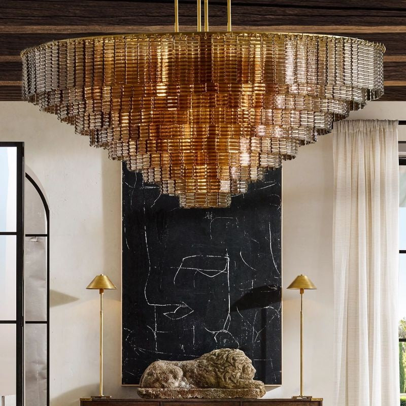 The collection's chandeliers combine traditional glassmaking techniques with modernist style. It is a study in geometric repetition, with textured ribbons of cast glass cascading in concentric circles, casting a warm glow to stunning effect.